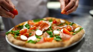 Questa foto mostra una pizza con il prosciutto crudo e la rucola e i pomodorini.
